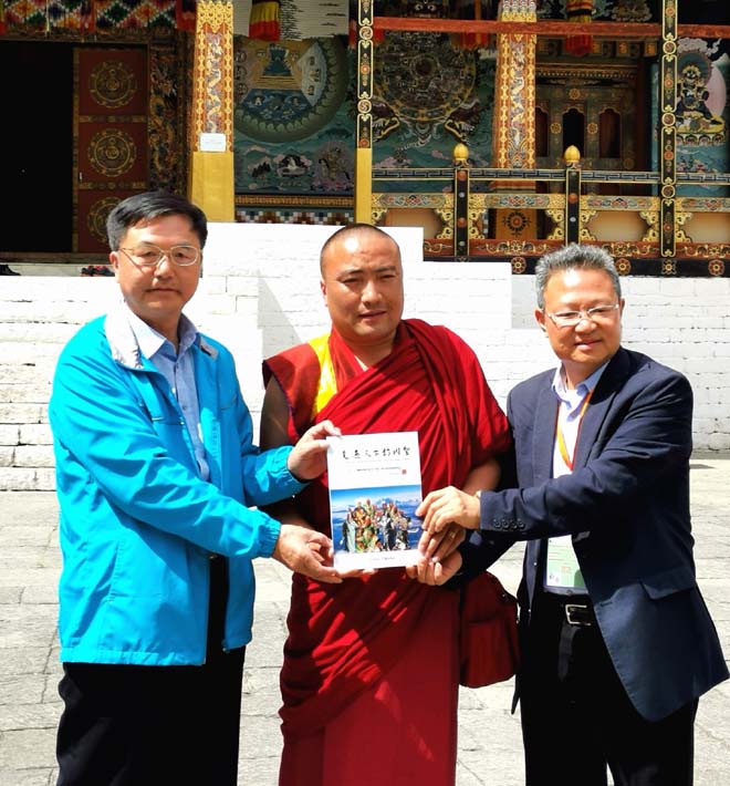 在不丹王宫，朱正明向国师特别助理、乌金堪布Khenpo Ugyen tenzin drukdra（中）赠送《走遍天下访关圣》西藏版，右为美国儒商会会长、爱国侨领陈绍恭先生（南亚摄影）.jpg